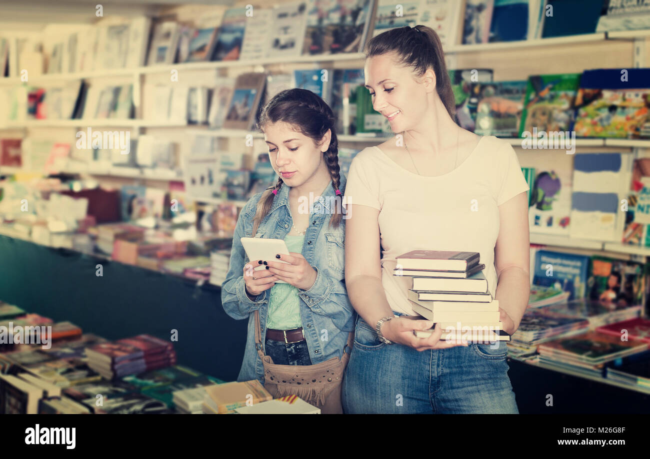 Mutter mit Schulmädchen plaudern auf Tablet und Shopping literatur Bücher Stockfoto