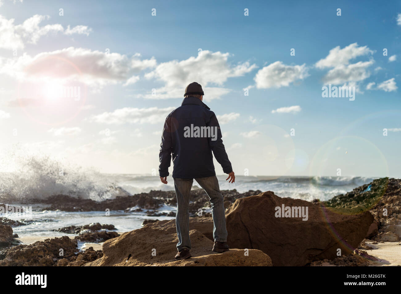 Männliche Explorer steht auf Felsen brechenden Wellen beobachten, Silhouette. Stockfoto