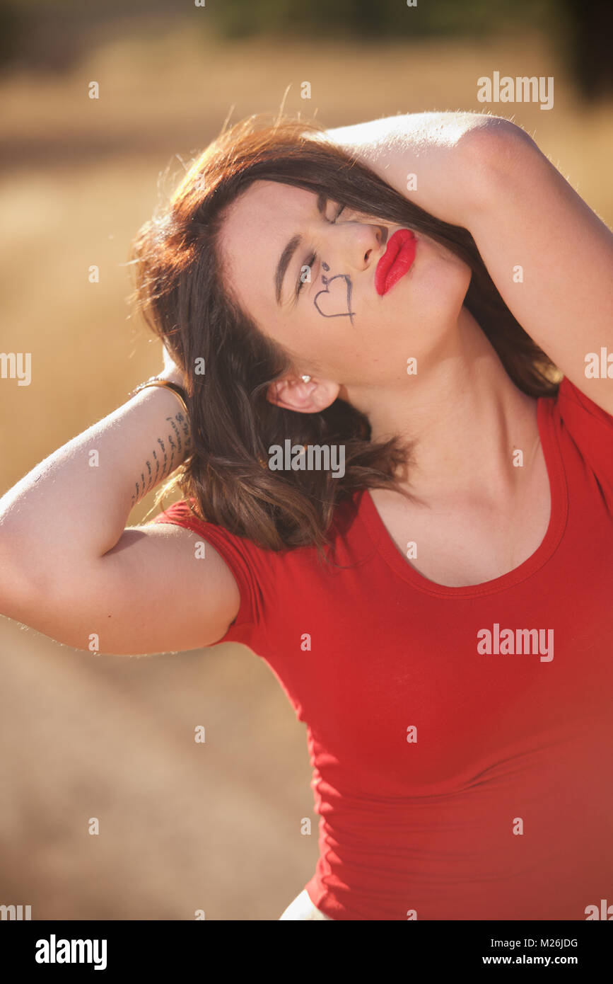 Schöne brünette Mädchen - Kopf und Schultern trägt ein rotes T-Shirt und auf dem Land. Stockfoto