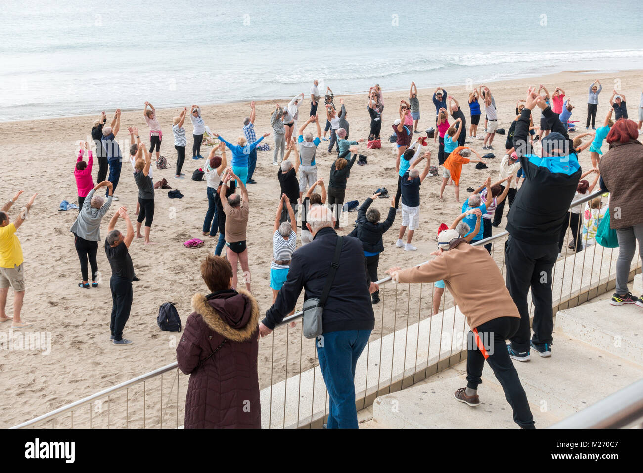 Senioren fit halten am Strand in Benidorm, Spanien. Männer Frauen Senioren, ältere Fitness klasse Zuschauer und einzusteigen. Stockfoto