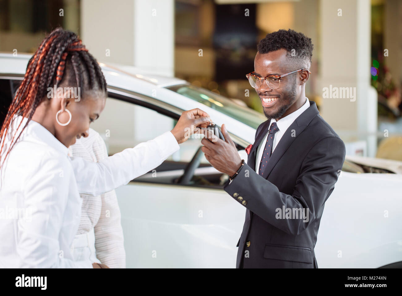 Absatzlage im Autohaus, junge afrikanische Paar erhält der Schlüssel für neue Pkw Stockfoto