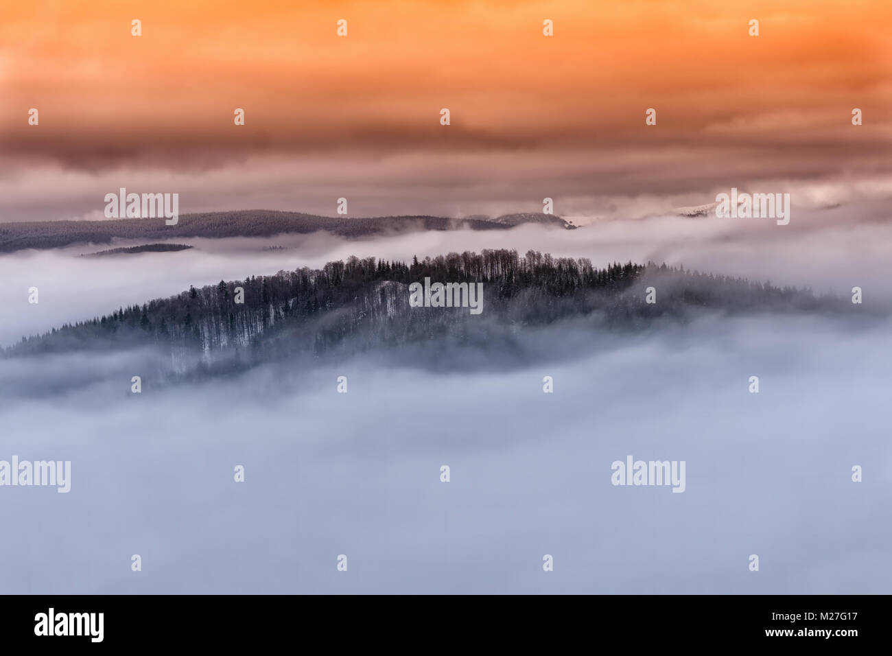 Winter nebligen Berglandschaft. Märchen Sonnenuntergang mit dramatischen Wolken im Orange Sky Stockfoto