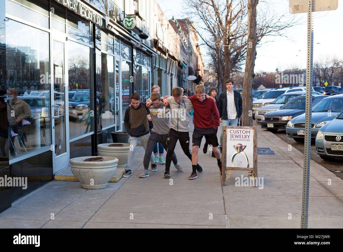 Eine Gruppe von Freunden sperrt Arme und umgehen Sie den Bürgersteig in Fort Collins, Colorado, USA. Stockfoto