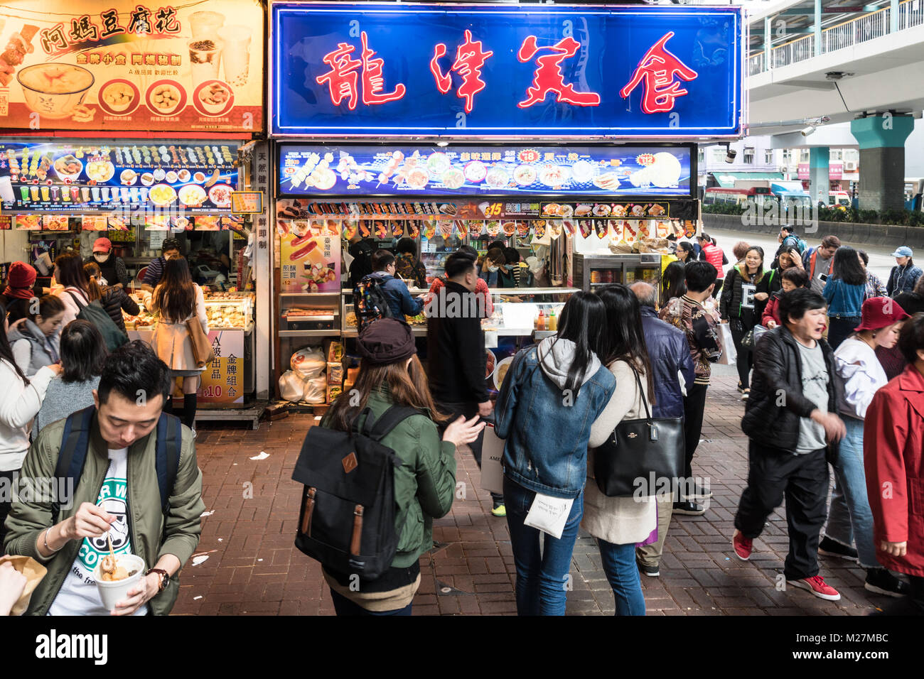 Hongkong - 25. Januar 2018: Menschen kaufen verschiedenen Street Food Snacks wie Fisch und Fleisch Kugeln auf Spießen, in einem Stall in den überfüllten Straßen von Mong Stockfoto