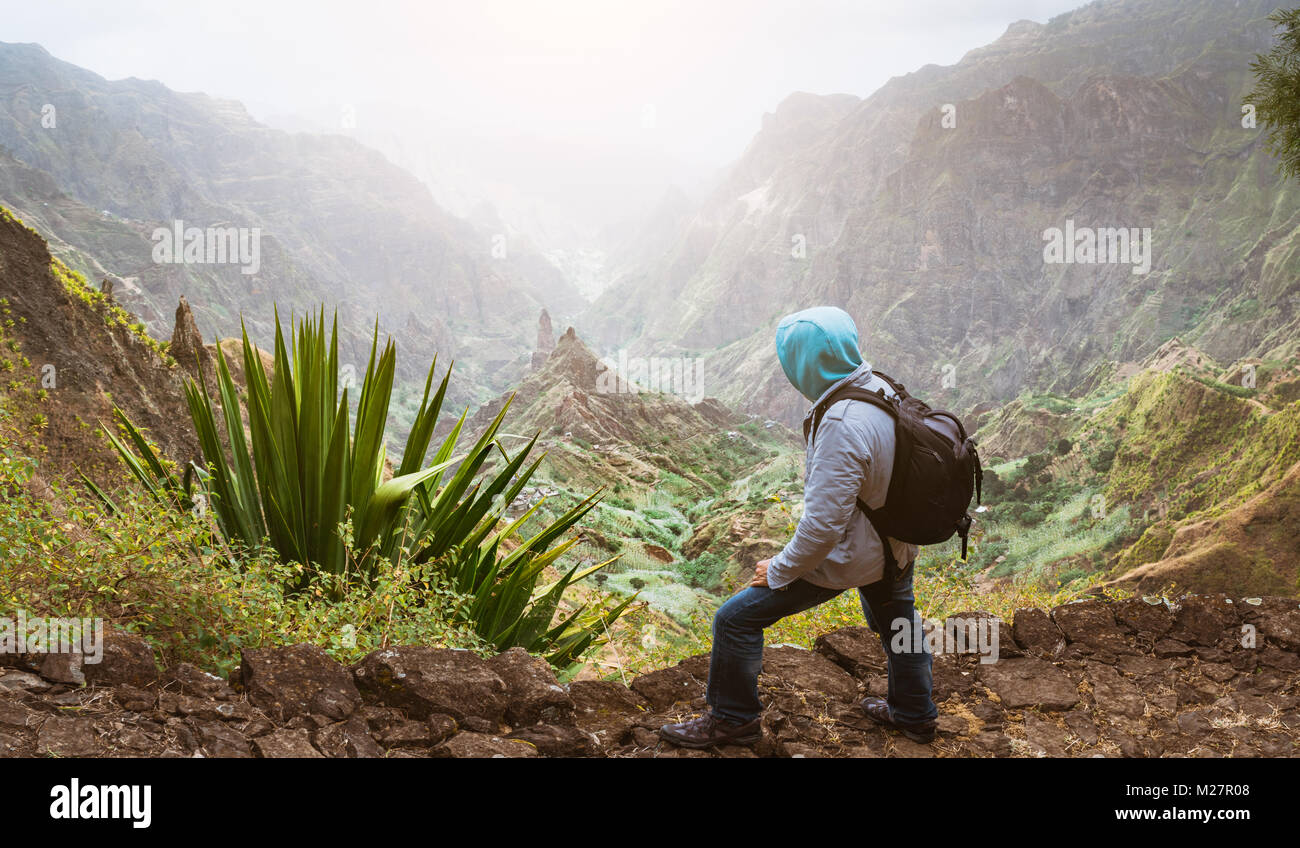 Reisende mit Rucksack über die ländliche Landschaft mit Bergen und Schlucht im Staub der Luft auf dem Weg von Xo-Xo Tal. Santo Antao, Kap Verde Stockfoto