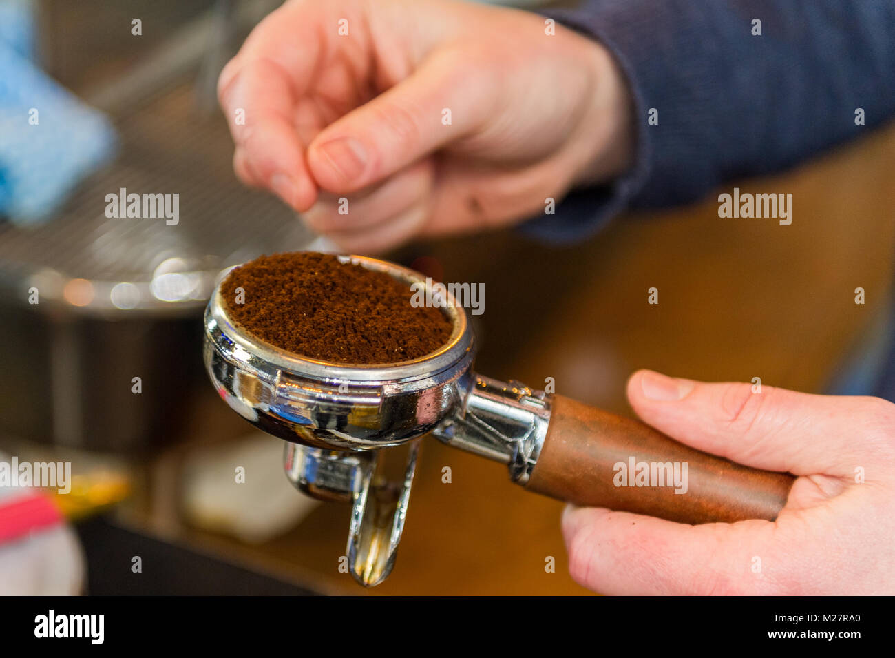 Barista füllen eine Kaffeemaschine mit Kaffee mahlt, bevor Sie eine Tasse Kaffee mit einer handelsüblichen Kaffeemaschine close-up. Stockfoto