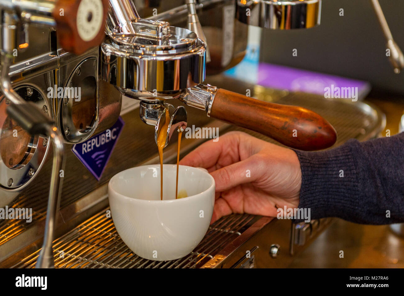 Kaffee gießen in die Schale, die von einem professionellen Barista über eine Kaffeemaschine. Stockfoto