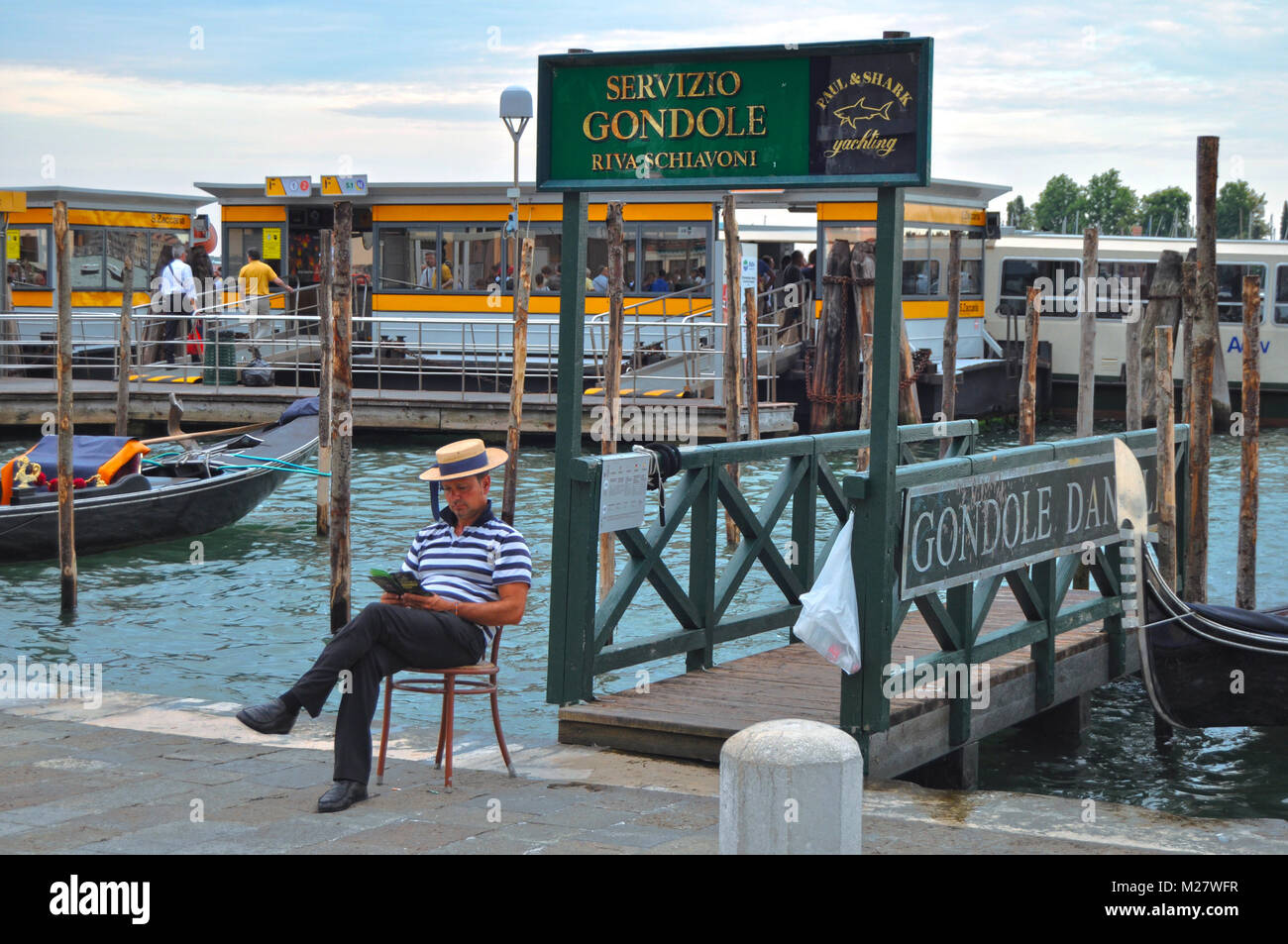 Venedig, Italien - 14.August 2014: ein gondoliere ist ein Buch lesen, sitzen unter dem Zeichen ervizio Gondole" (Gondeln) wartenden Kunden. Stockfoto
