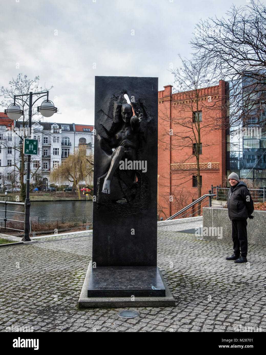 Berlin, Mitte, Moabit. Bronze Skulptur von Menschen durch die Wand von Rolf Bibi-Symbol des Mauerfalls in Berlin auf der Straße der Erinnerung. Stockfoto