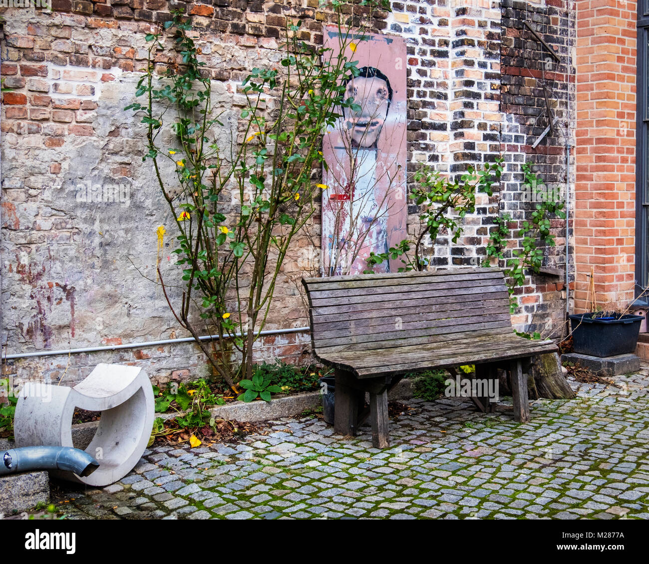 Berlin, Prenzlauerberg, Innenhof der ehemaligen Königstadt Brauerei. Sitzbereich im Freien mit Sitzbank & Kunst auf der alten Mauer. Stockfoto