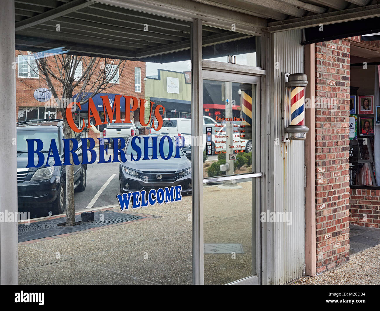 Vordere äußere Eingang des Campus Friseur Geschäft mit beleuchteten barber Pole in Auburn, Alabama, USA. Stockfoto