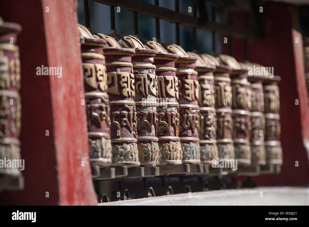Heiligen tibetischen Gebetsmühlen ordnen in Zeile für Personen, die Rollen im Tempel Stockfoto