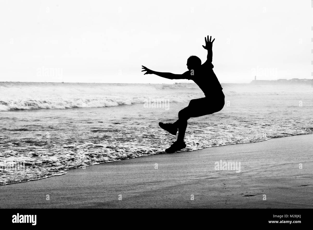 Junger Mann an einem Strand springen Stockfoto