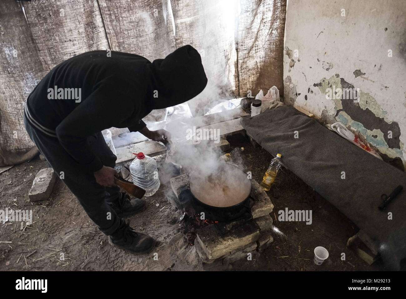 Horgos, Kanjiza, Serbien. 27 Jan, 2018. Zubereitung von Essen auf offenem Feuer ein Wanderarbeitnehmer aus Pakistan Köche ein Abendessen für seine Freunde. In Pakistan links, wenn er war 15 Jahre alt - dieser junge Mann war auf der Reise in jedem Land verzögert und nun findet er sich 21 Jahre - alt und klemmt in Serbien. horgos ist ein Dorf in Kanjiza Gemeinde befindet sich im nördlichen Banat Bezirk von Serbien, weniger als 10 km von der serbisch-ungarischen Grenze. Die balkanroute wurde offiziell vor über einem Jahr geschlossen mit Kroatien und Ungarn Erhöhung der Sicherheit der Grenzen, die Migranten und Flüchtlinge immer klemmt Ich hat Stockfoto