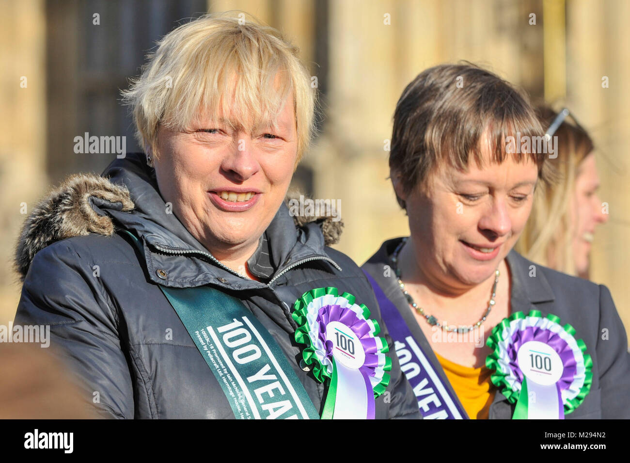 London, Großbritannien. Vom 6. Februar 2018. Maria Adler und Angela Eagle melden Sie weibliche Mitglieder des Schattenkabinetts und Arbeit Politiker außerhalb der Häuser des Parlaments, tragende Arbeit gestaltete suffragette Rosetten, Plakate neben einem "100 Jahre Frauen stimmen Banner unterstützen Sie die Einführung der Kampagne 100 Jahre Frauenwahlrecht feiern. Credit: Stephen Chung/Alamy leben Nachrichten Stockfoto