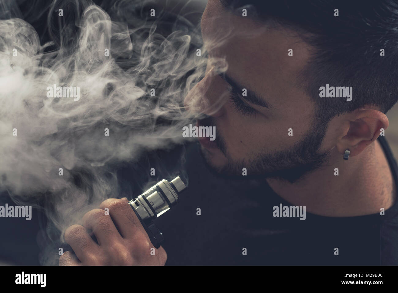 Hand, die eine elektronische Zigarette über einen dunklen Hintergrund Stockfoto