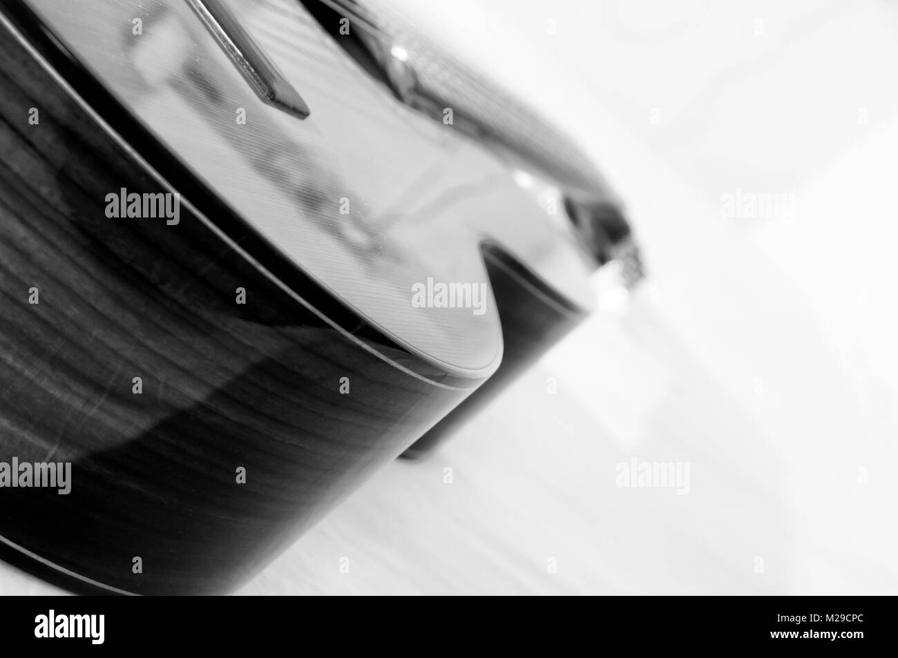 Schwarz-weiß Foto von einer klassischen Gitarre mit einem weißen Hintergrund. Stockfoto