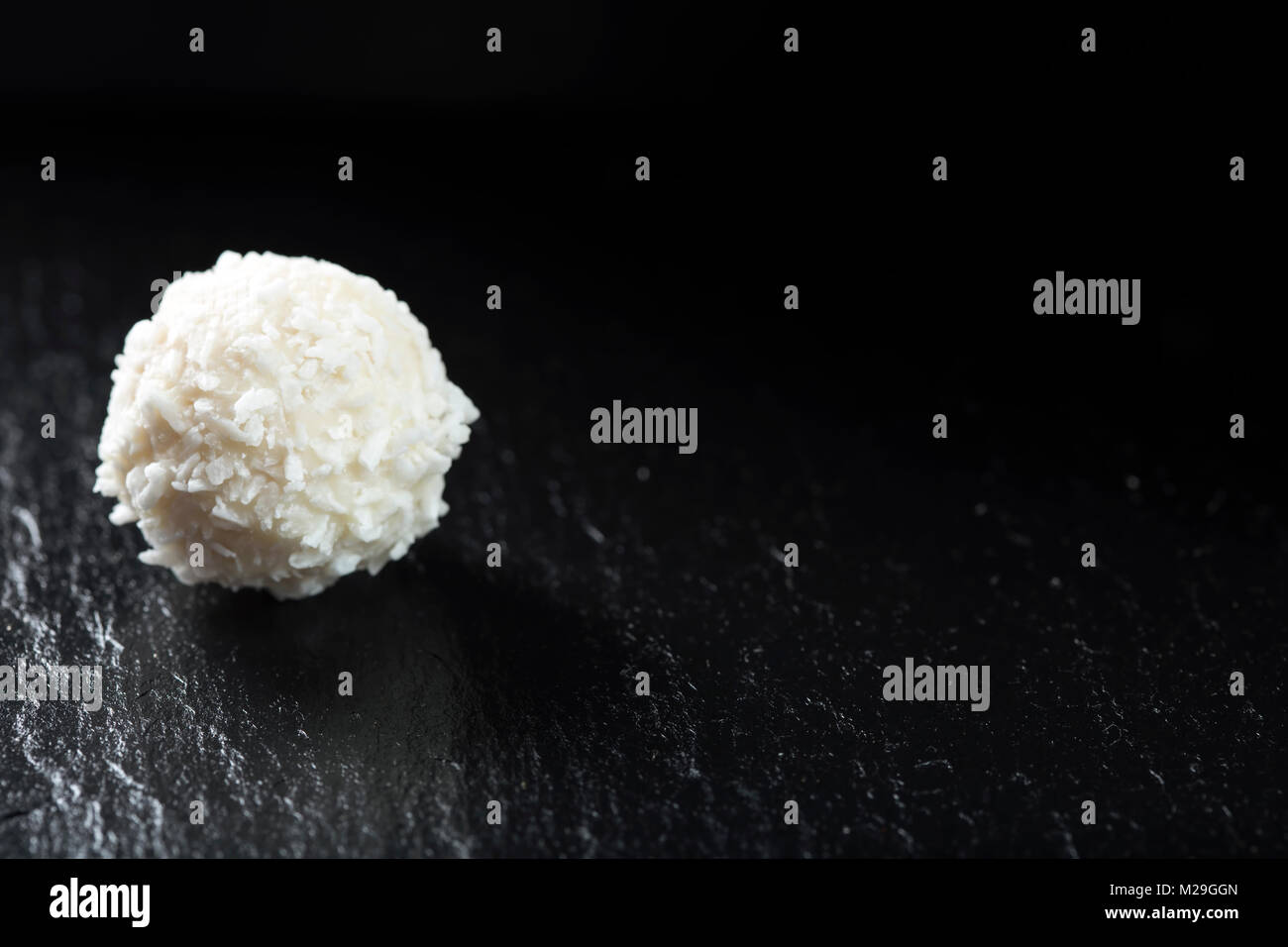 Raffaello weiße Süßigkeit mit Kokosraspeln auf einer Schiefertafel dunklen Hintergrund Stockfoto