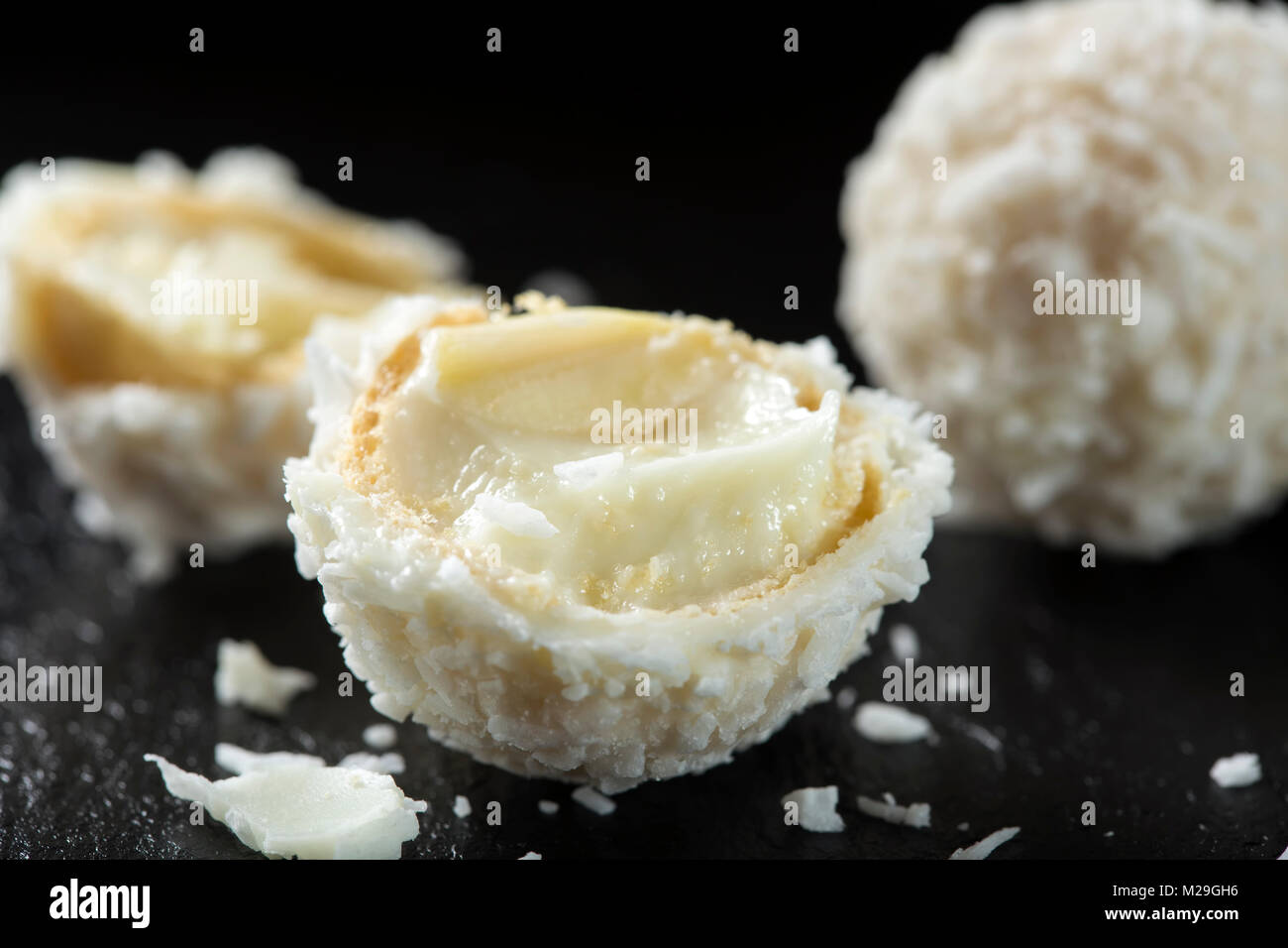 In der Nähe von Broken Raffaello weiße Süßigkeit mit Kokosraspeln auf einer Schiefertafel dunklen Hintergrund Stockfoto