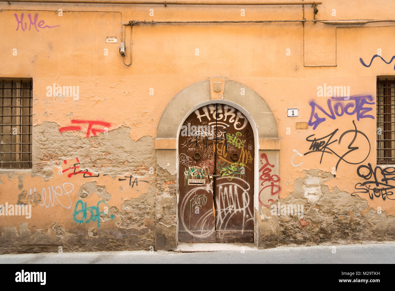 Graffiti gesprüht in weißer Farbe auf eine alte hölzerne Tür in Bologna, Italien Stockfoto