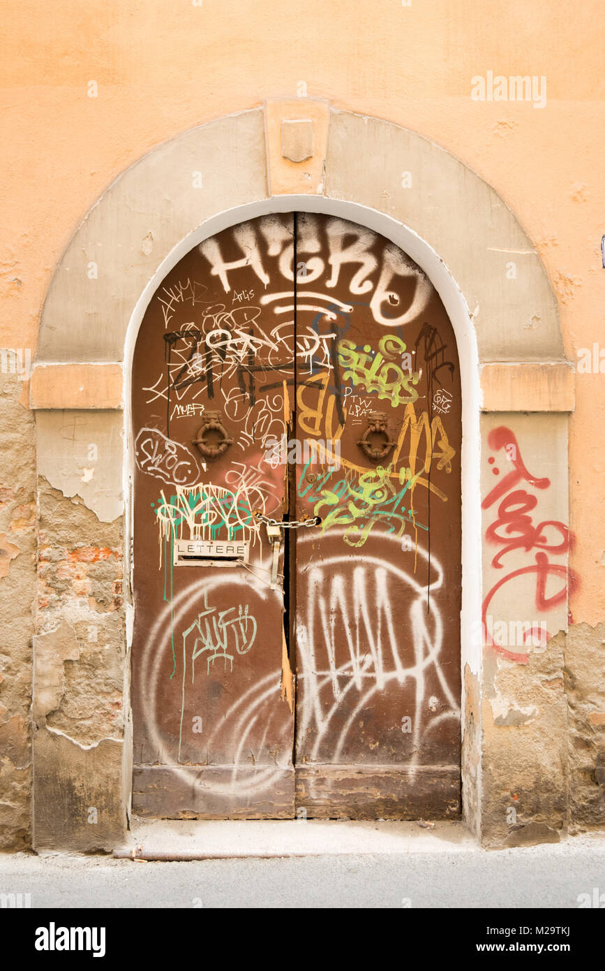 Graffiti gesprüht in weißer Farbe auf eine alte hölzerne Tür in Bologna, Italien Stockfoto