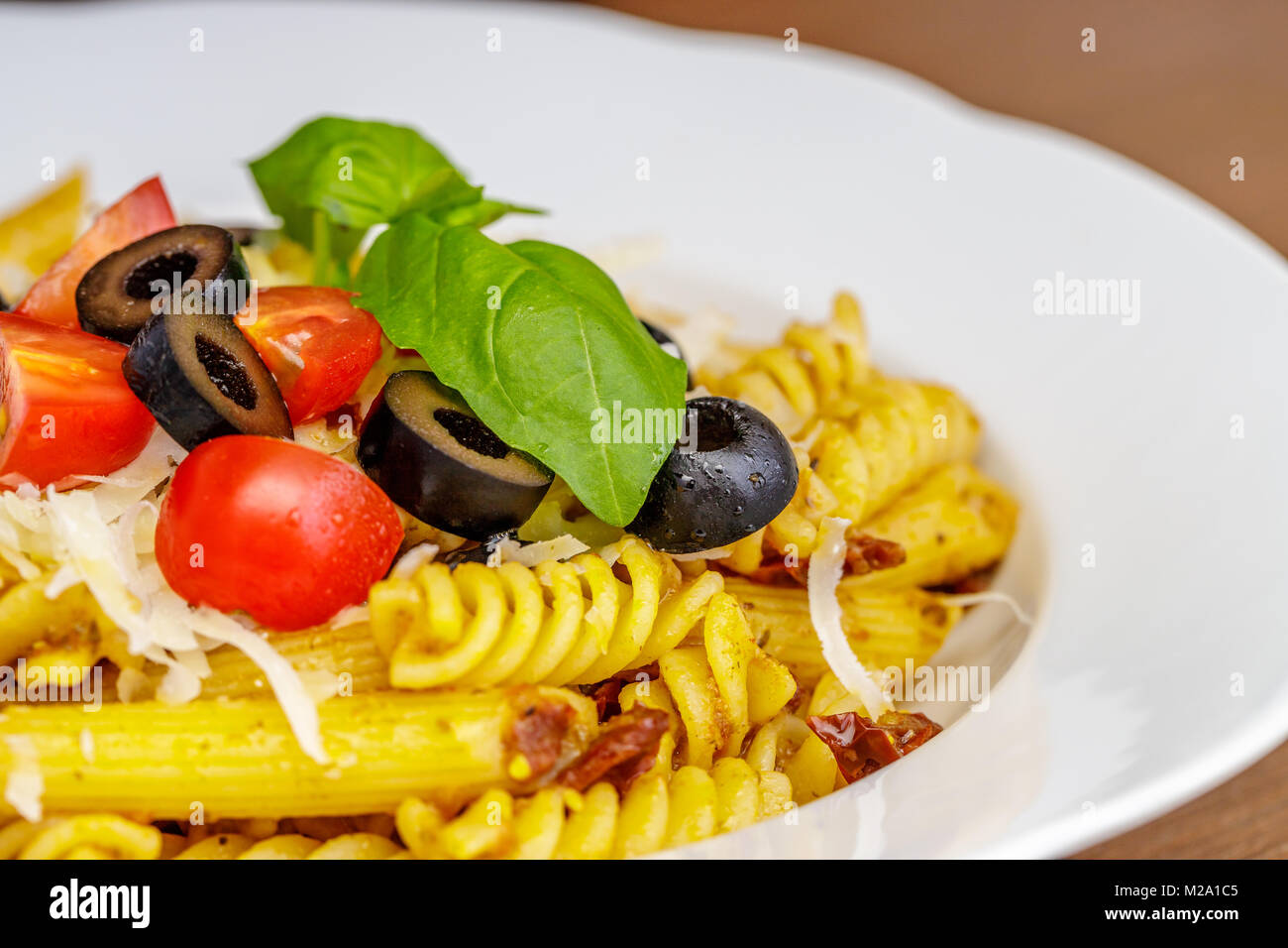 Penne und Fusilli Pasta mit Tomaten, Olivenöl, Parmesan und Basilikum. Stockfoto