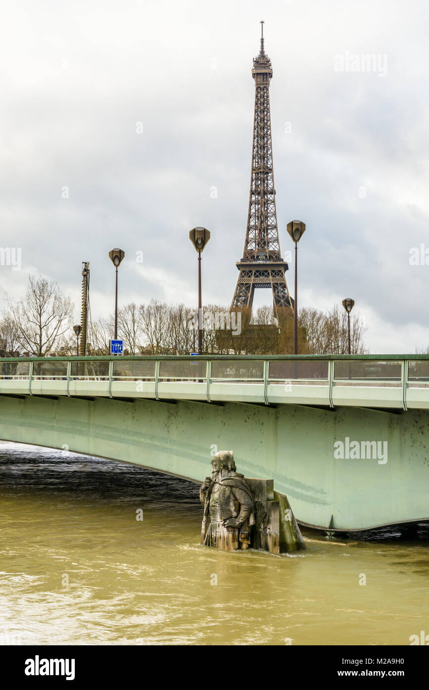 Das Alma-Brücke und die Hälfte getaucht Statue 'Le Zouave" während eines Winters Flut von der Seine und dem Eiffelturm in der Ferne unter einen bewölkten Himmel. Stockfoto