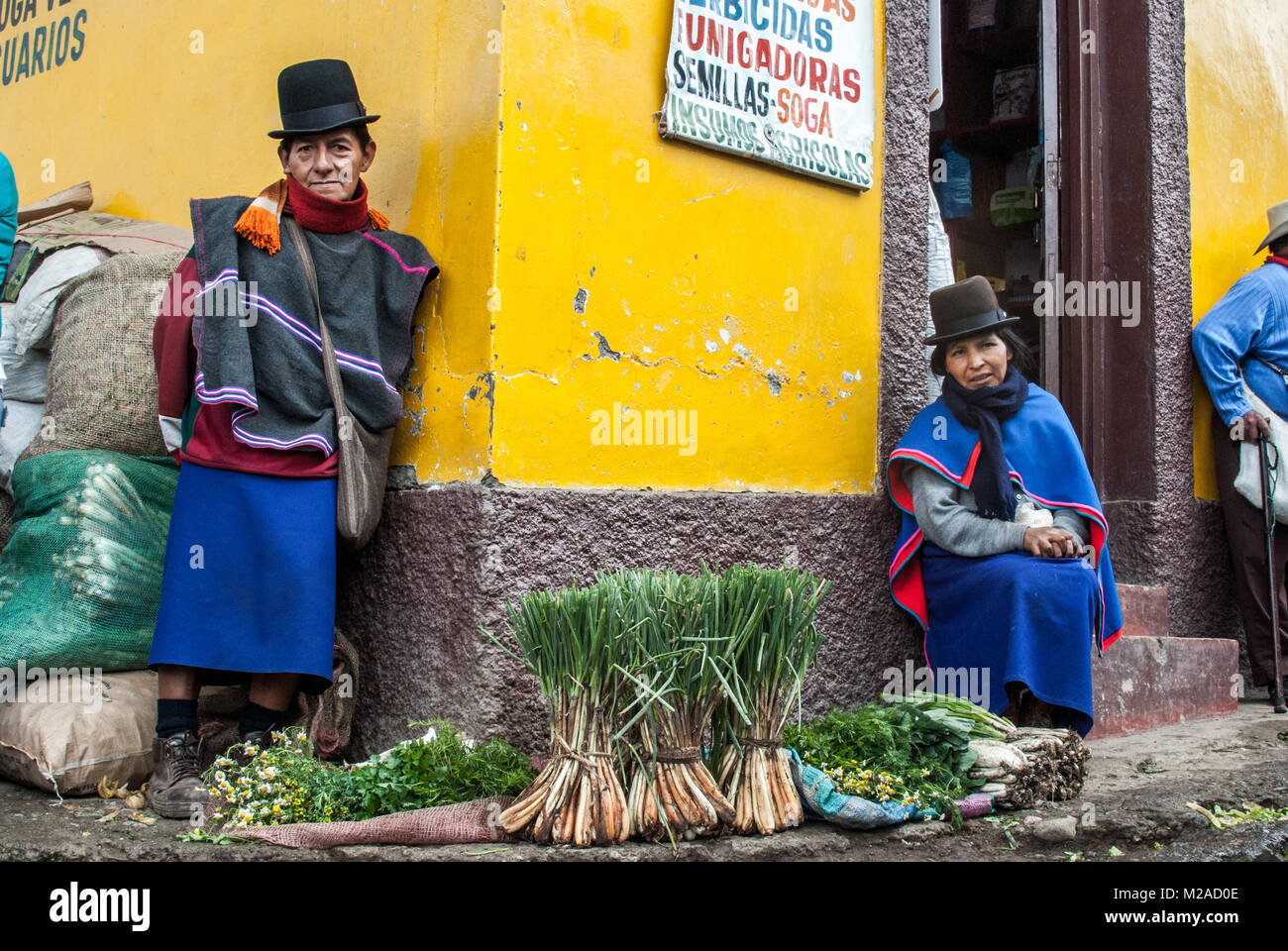 Ein guambiano indigenen Paar Verkauf produzieren, die vor einem hellen gelben wand in Silvia, Kolumbien Stockfoto