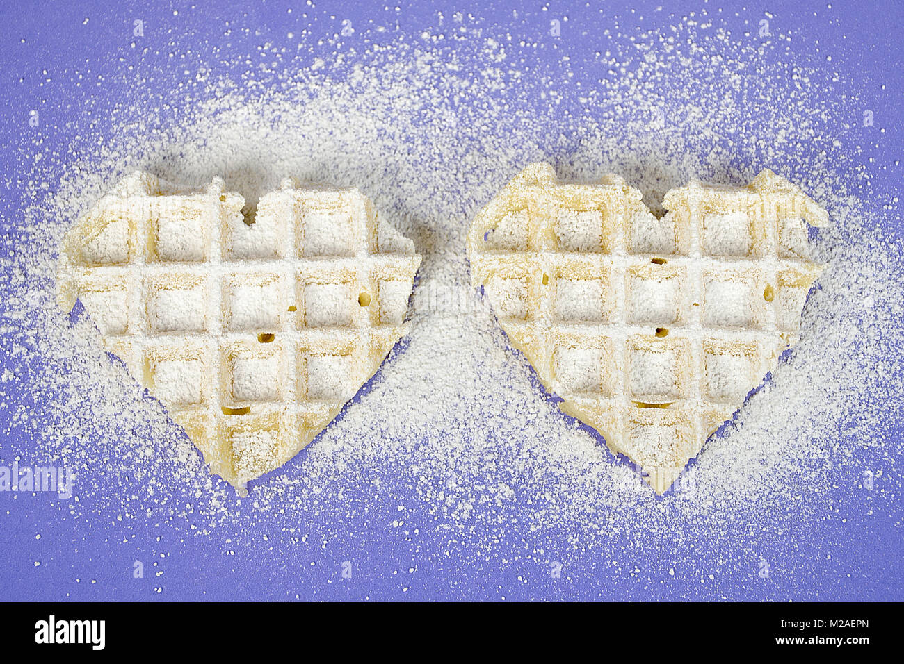 Paar Waffeln Herzen bestreut mit Konditoren Zucker auf lila Hintergrund Stockfoto