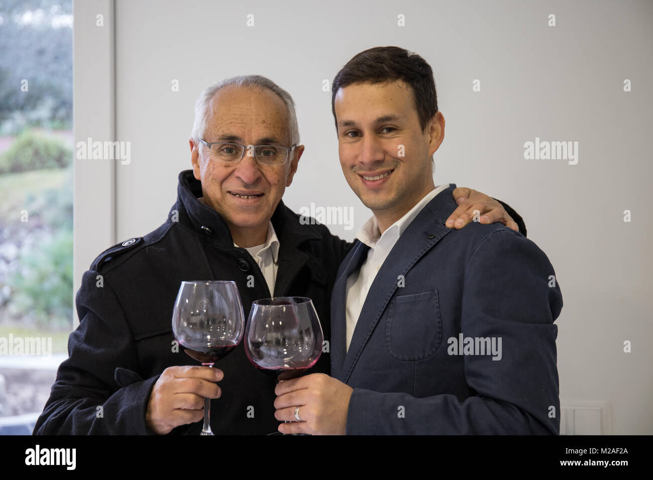 Vater und Sohn trinkt ein Glas Wein in der Küche zu Hause. Stockfoto