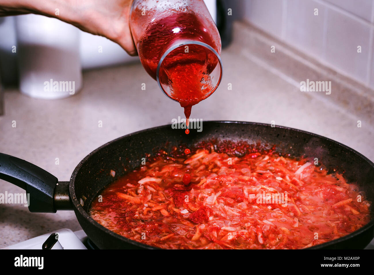 Hinzufügen von Tomatenmark zu Gemüse für Borscht Stockfoto