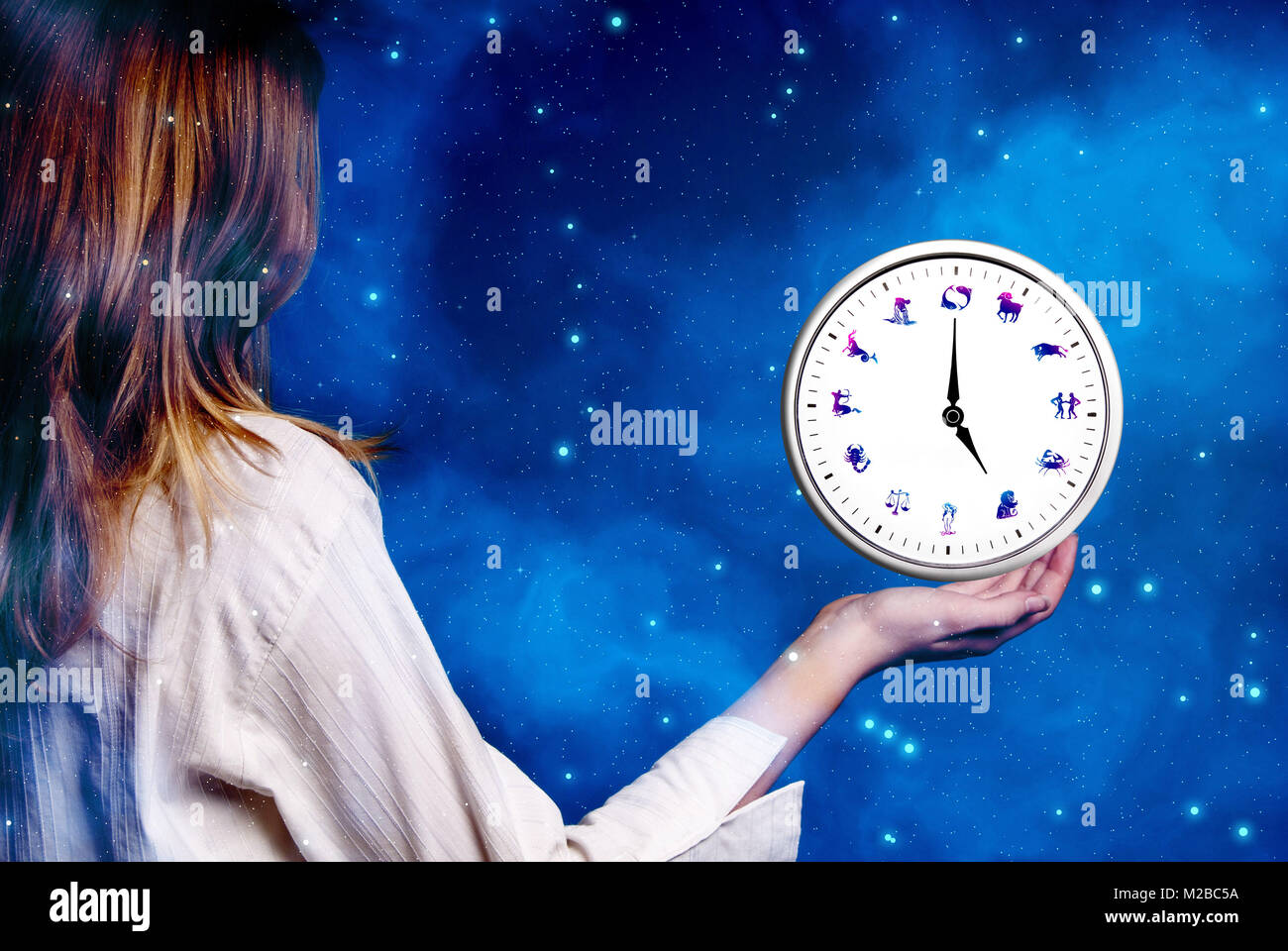 Blonde Mädchen Holding über ihre Hand eine Astrologische Uhr mit allen Zeichen des Tierkreises Stockfoto