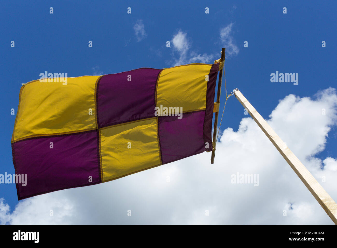 Gelb und Violett Flagge auf einer Fahne schwingen gegen den Wind auf einer klaren und hellen Tag Stockfoto