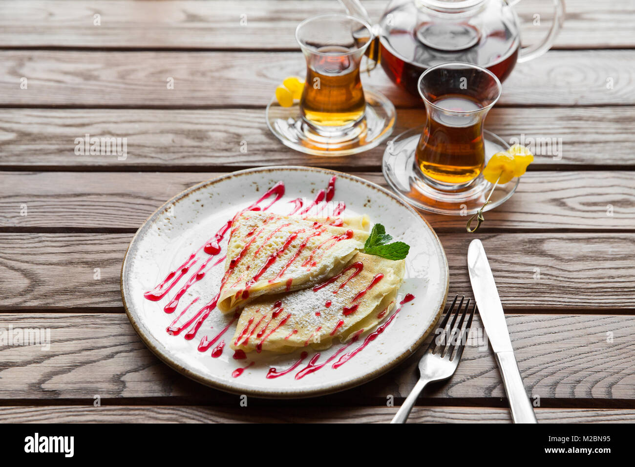 Leckere dünne Pfannkuchen serviert mit Erdbeersauce auf einer hölzernen ...