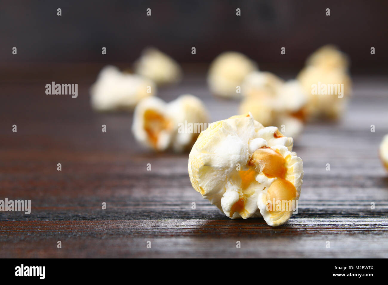 Samen von gesalzenem Popcorn auf einem Holztisch Stockfoto