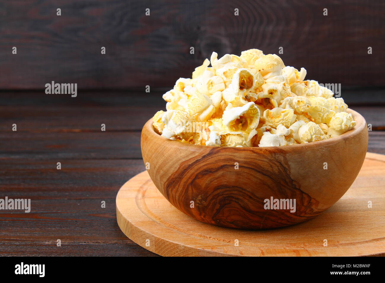 Gesalzene Popcorn in eine hölzerne Schüssel auf einen hölzernen Tisch Stockfoto