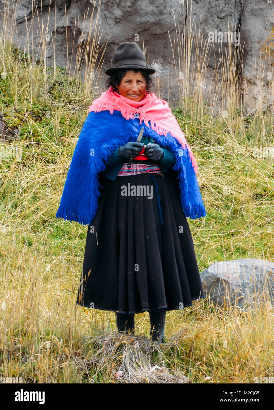 Chimborazo, Ecuador, 20. Dezember 2017: Traditionell gekleidete Ecuadorianische Frau Knoblauch schälen auf der Seite einer Straße Stockfoto