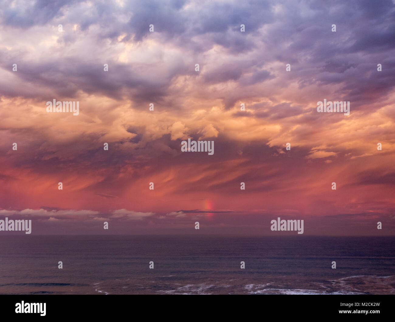 Stürmischen Himmel und vertikale Regenbogen über dem Meer bei Sonnenuntergang. Stockfoto