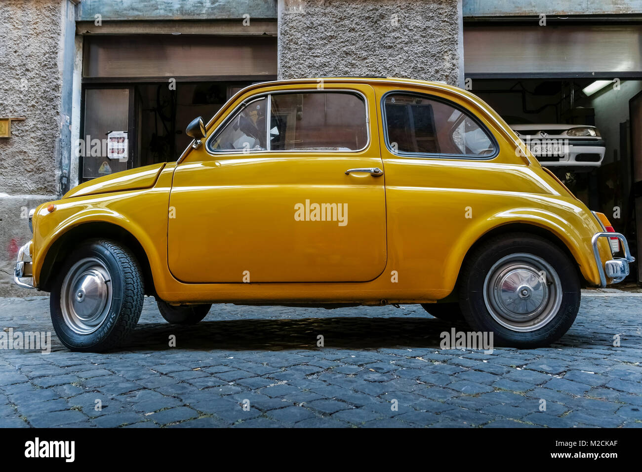 Fiat 500 hergestellt im Jahr 1970. Alter Stil, klassisch, vintage, Retro-Auto. Gelbe Farbe. Geparkt vor einer Autowerkstatt in Rom, Italien, EU. Seitenansicht. Stockfoto