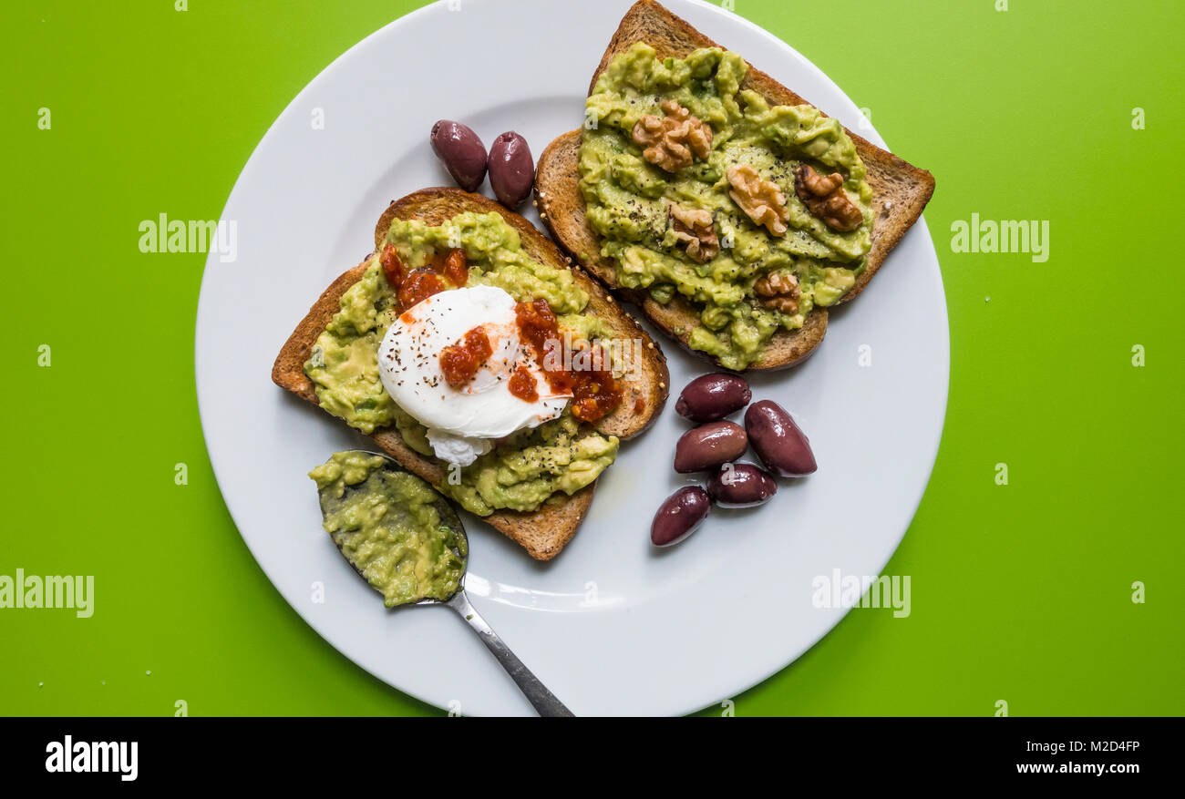 Avocado Toast mit pochiertem Ei, Kalamata Oliven und Walnüssen und einer würzigen roten Dressing Stockfoto