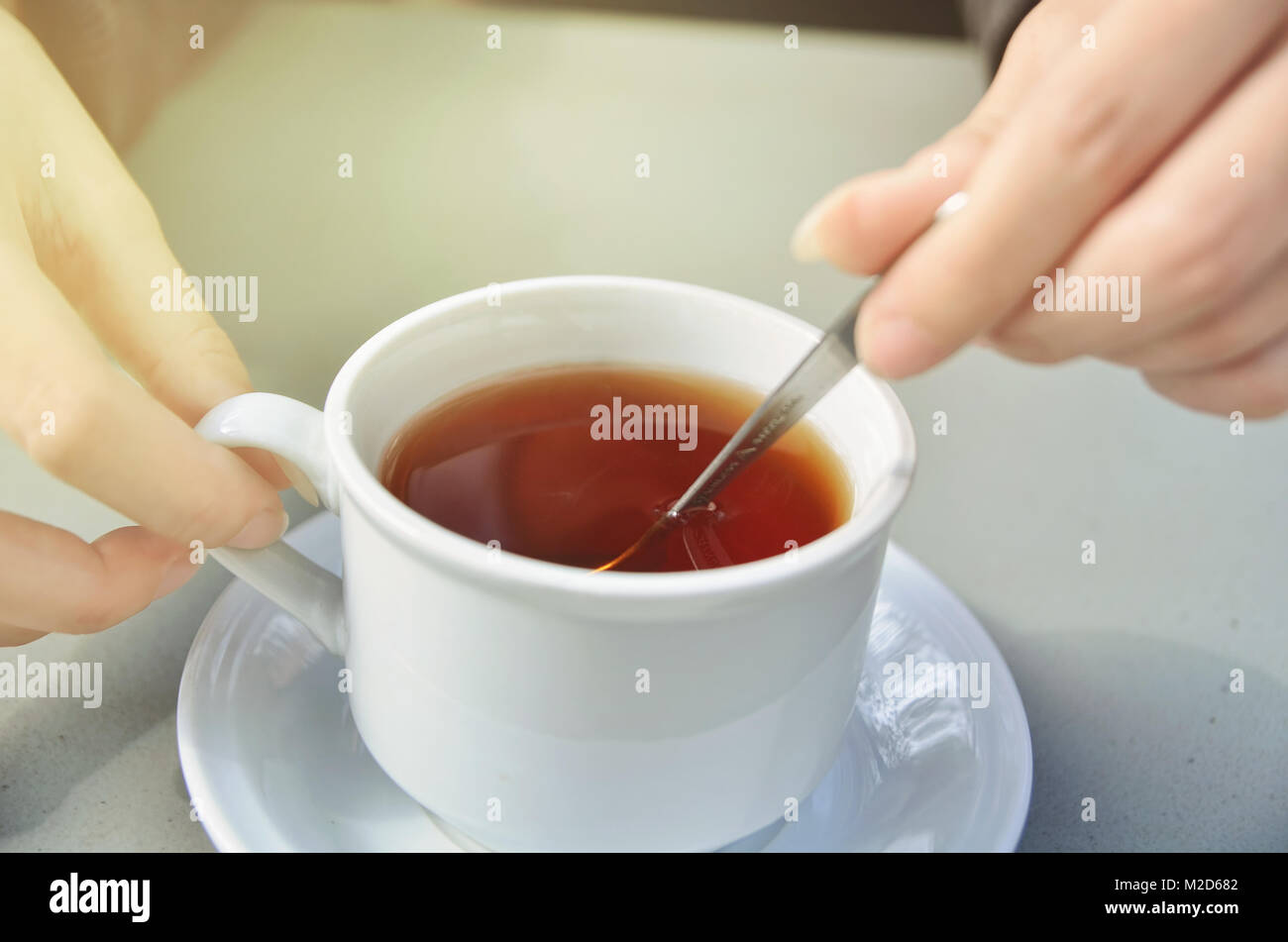 Die Mädchen Hand rühren eine Tasse Tee Stockfoto