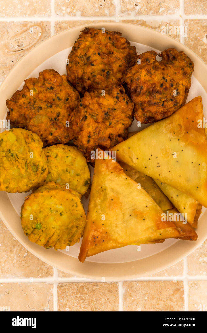 Indisches essen Snacks vegetarische Tikka vegetarische Samosa Zwiebel Bhaji auf eine geflieste Küche Tisch Stockfoto