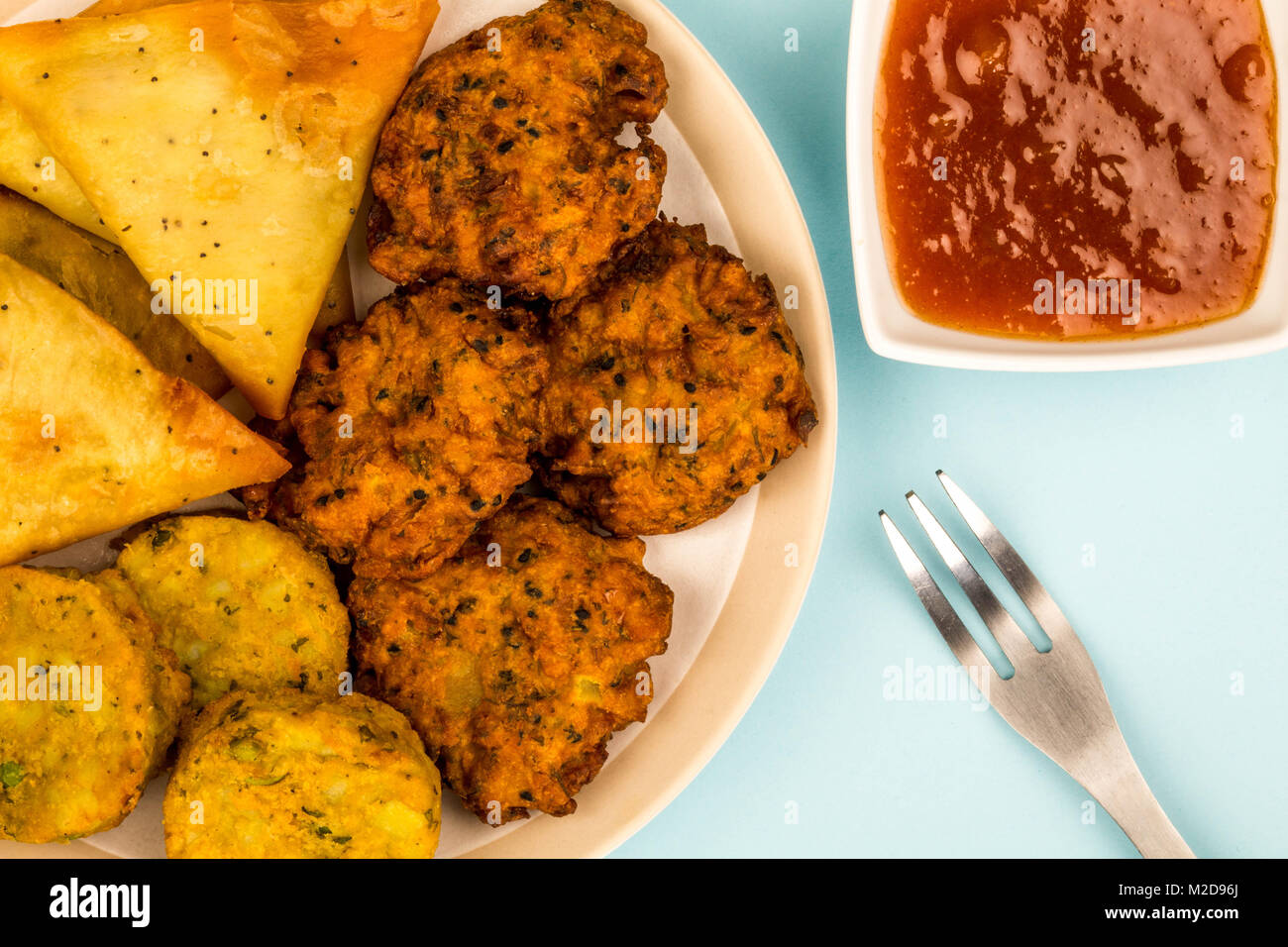 Indisches essen Snacks vegetarische Tikka vegetarische Samosa Zwiebel Bhaji gegen einen hellblauen Hintergrund Stockfoto