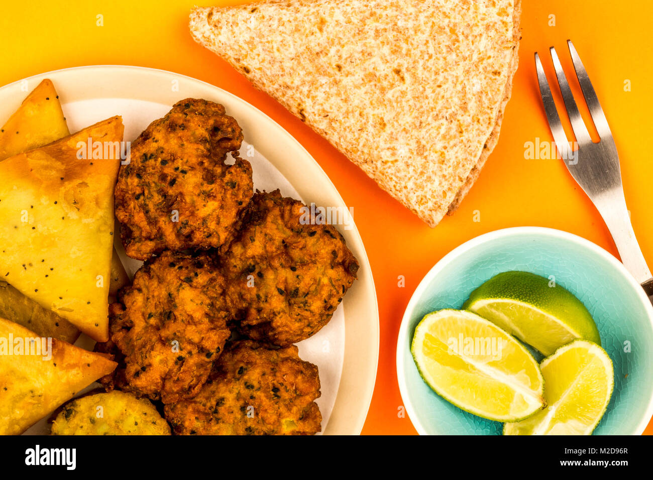 Indisches essen Snacks vegetarische Tikka vegetarische Samosa Zwiebel Bhaji mit chapatis Fladenbrot gegen einen orangen Hintergrund Stockfoto