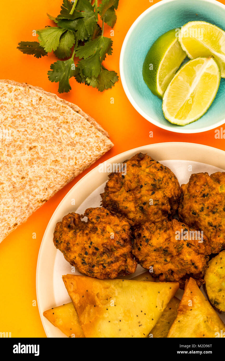 Indisches essen Snacks vegetarische Tikka vegetarische Samosa Zwiebel Bhaji mit chapatis Fladenbrot gegen einen orangen Hintergrund Stockfoto