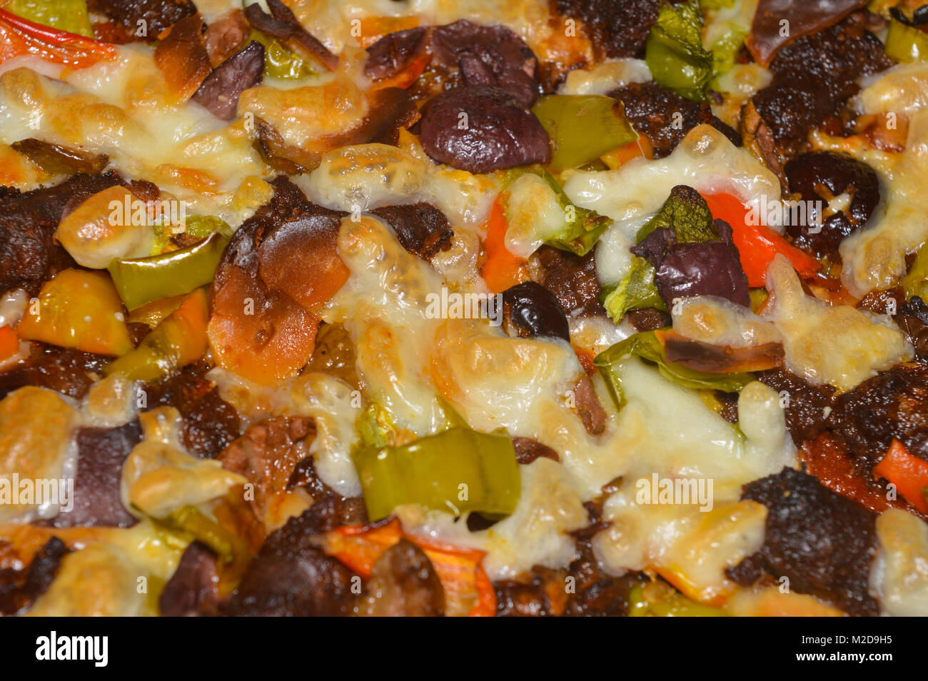 Hausgemachte Pizza mit Wurst, Käse, Tomaten und grüner Pfeffer Textur Hintergrund Stockfoto