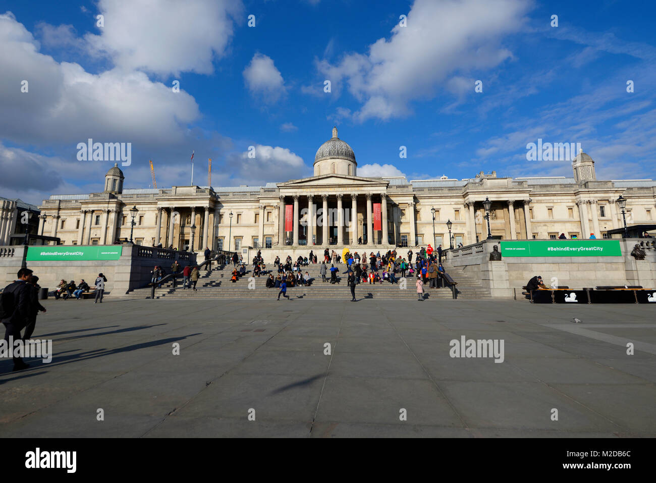 Bürgermeister von London, Hashtag, Hinter jeder großen Stadt, Slogan außerhalb der Nationalgalerie Trafalgar Square London mit Touristen, die den sonnigen Tag genießen Stockfoto