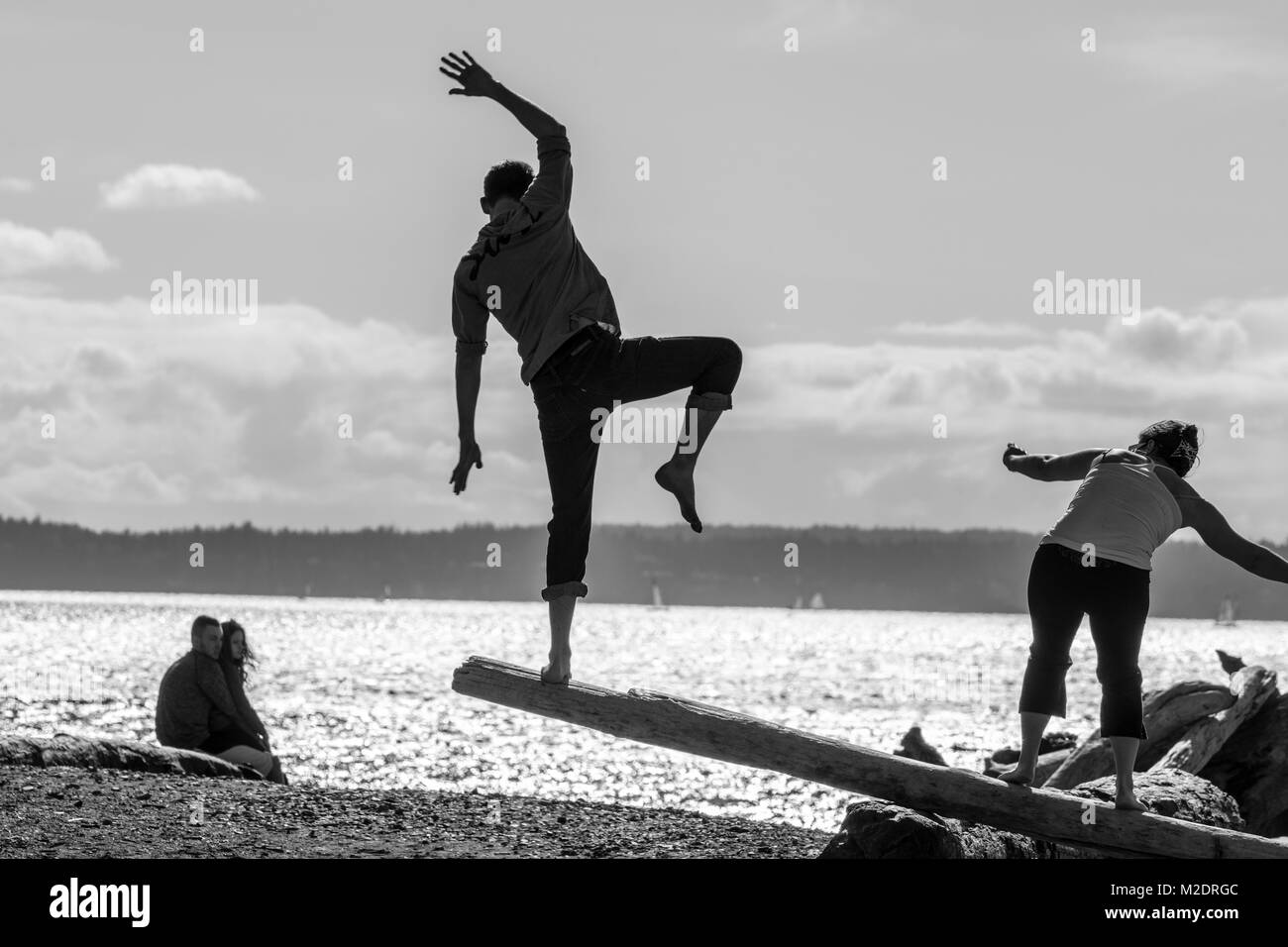 Usa, Washington, Seattle, Paar Balancieren auf einem Anmelden Carkeek Park. Puget Sound im Hintergrund Stockfoto