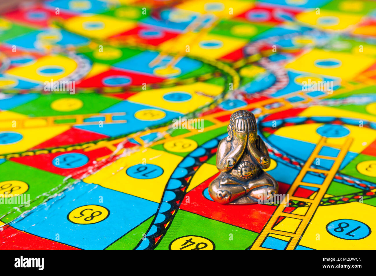 Retro Schlangen und Leitern mit Miniatur Buddha Figur in Einstellung Studio, Melbourne, Australien Stockfoto