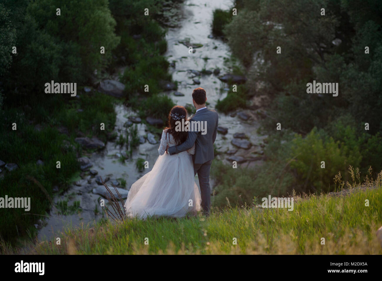 Kaukasische Braut und Bräutigam stehen auf Hügel bewundern Fluss Stockfoto